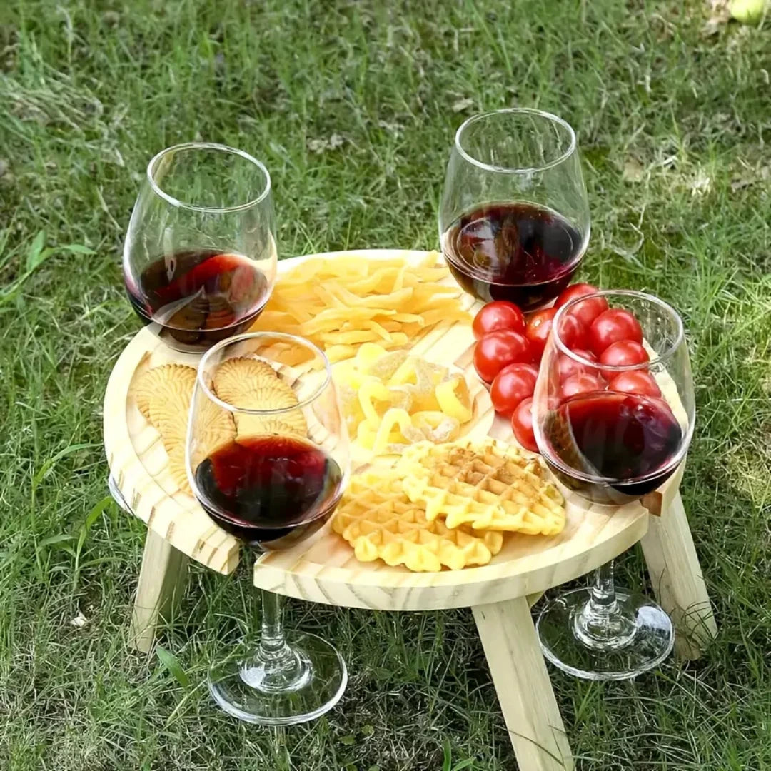 Mesa de madera plegable para picnic, ideal para disfrutar vinos y aperitivos al aire libre.
