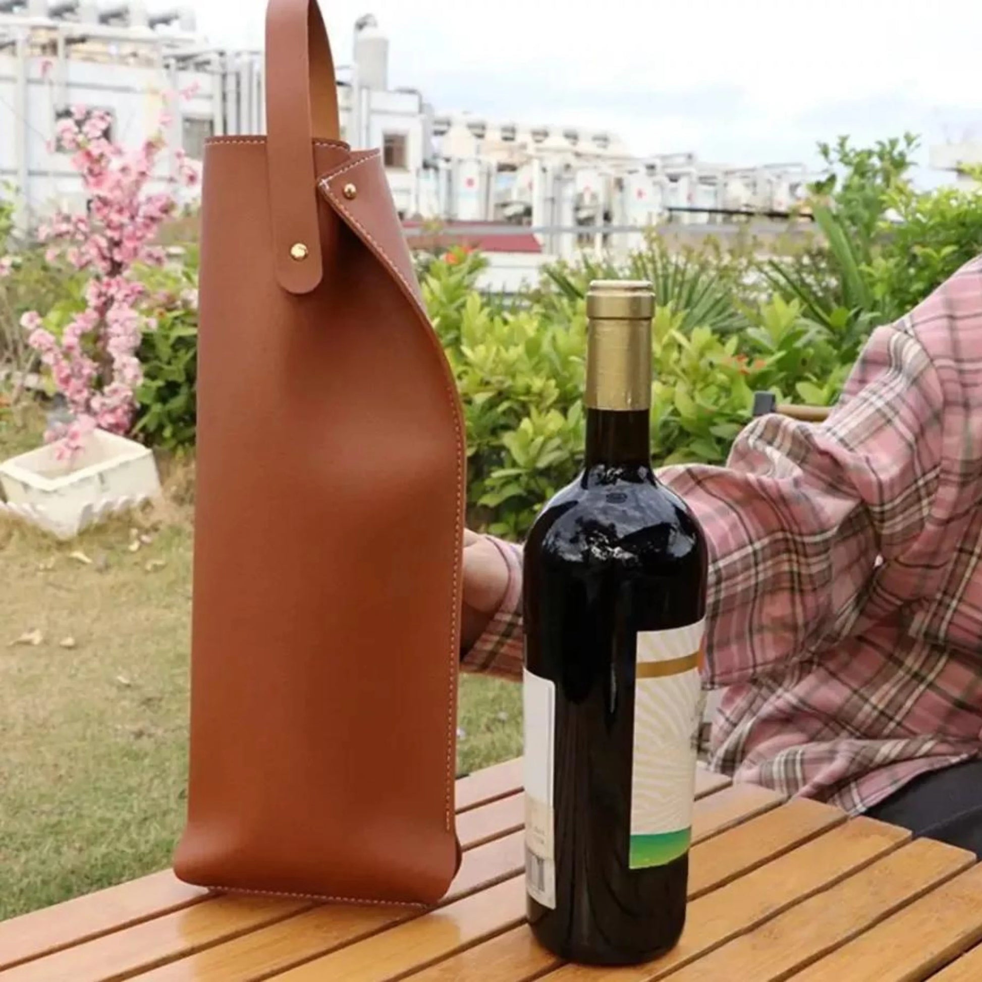 Bolsa para vino de ecocuero café sobre una mesa al aire libre