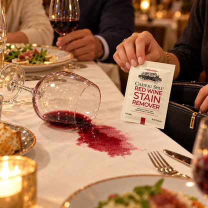 Copa de vino tinto derramada en una cena y una persona sacando una toallita Château Spill de su cartera